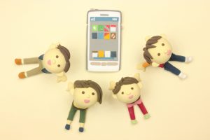 スマホ　スマホ囲む4人のお人形